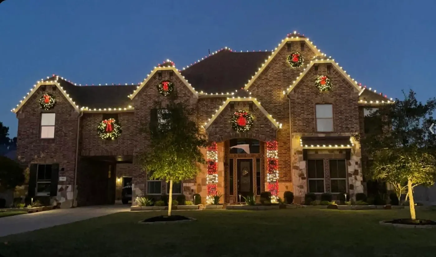 Very nice brick house with numerous wreaths over the gables, outlined roof
