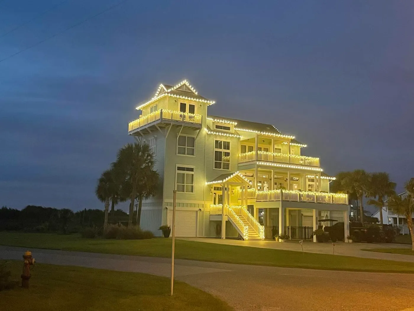 Four-story house with roof and decks wrapped in Christmas lights