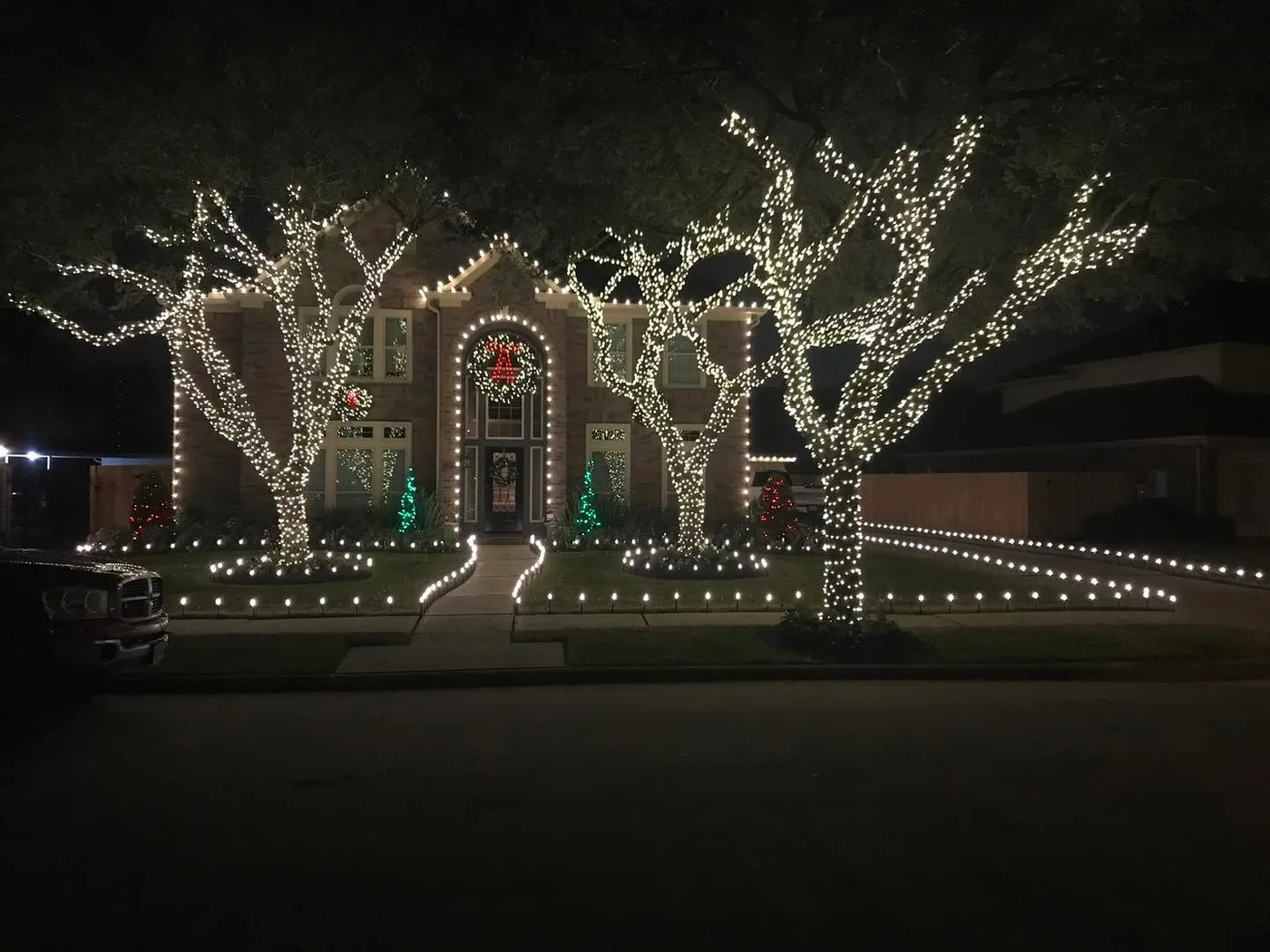 Oak trees wrapped with Christmas lights, house outlined in Christmas lights, landscaping also