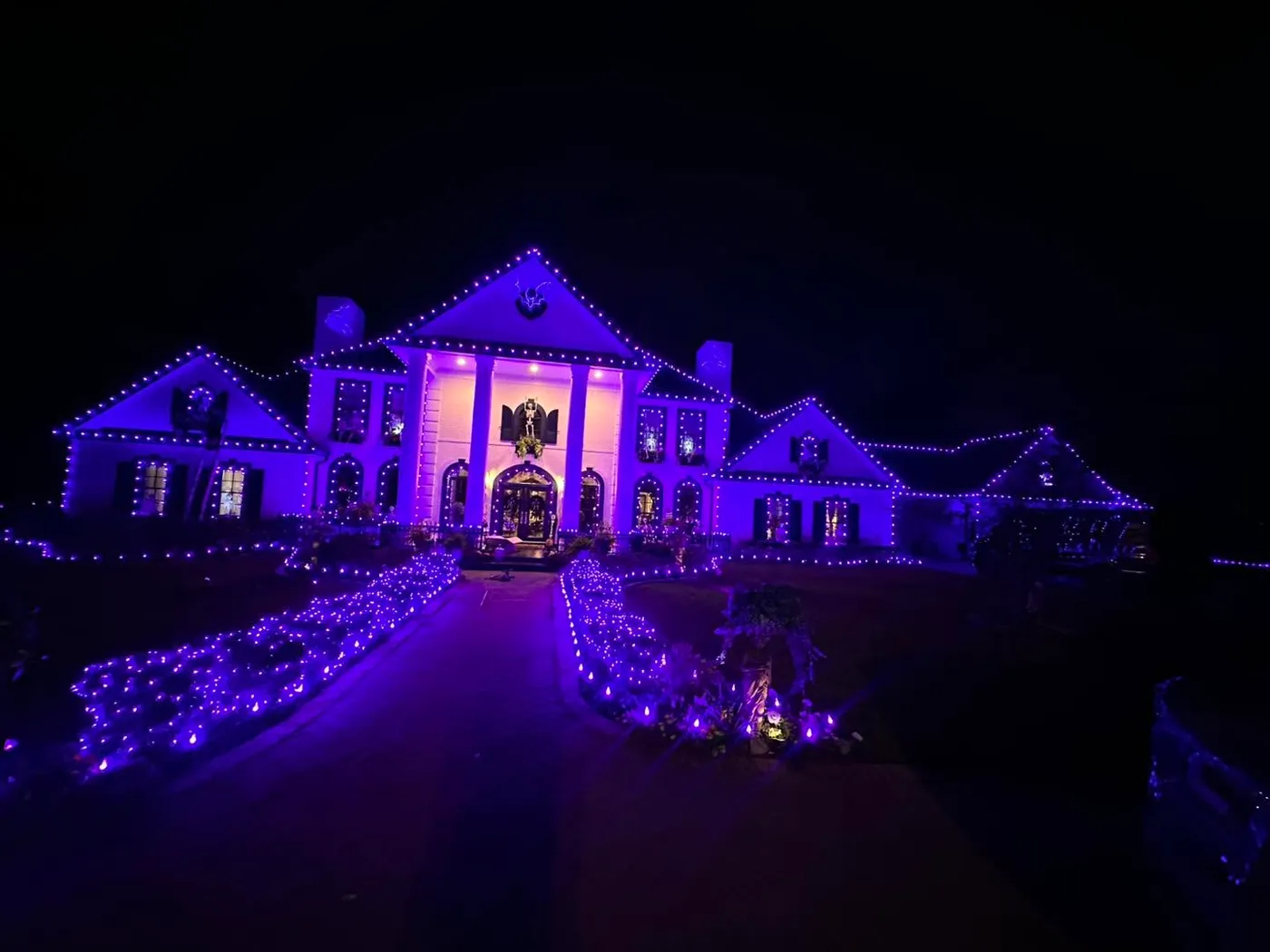 Palatial estate wrapped in Christmas lights with purple accent lighting