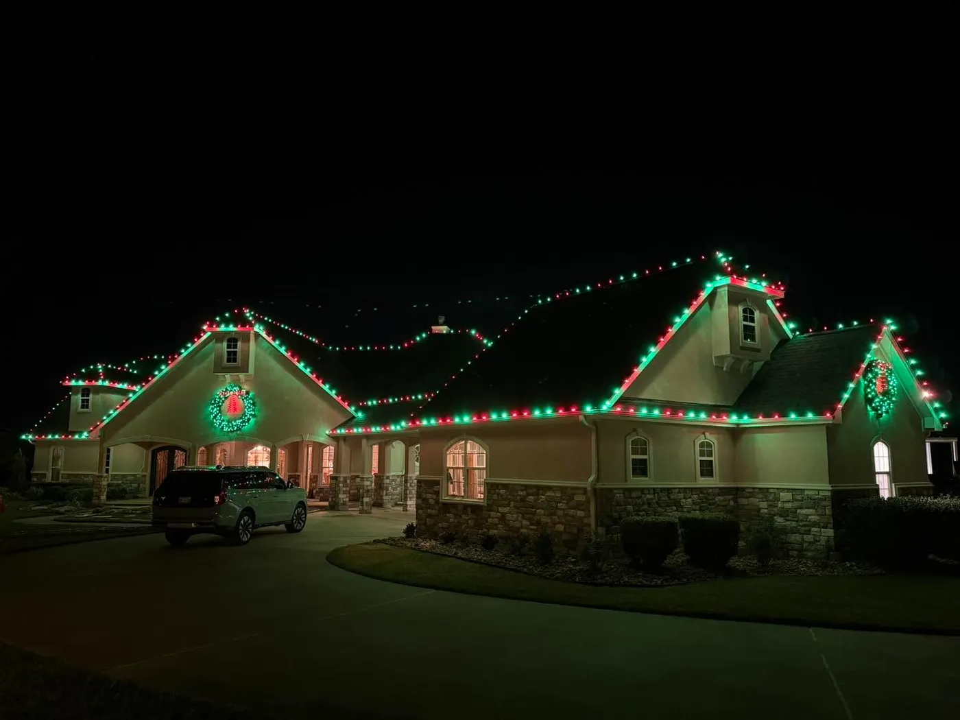 Ranch-style house roof line with Christmas lights and a large wreath on a gable
